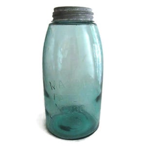 May include: A vintage green glass Mason jar with a silver lid. The jar has the text "MASON'S PATENT NOV. 30 1858" embossed on the side.