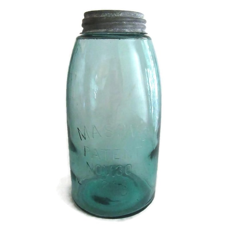 May include: A vintage green glass Mason jar with a silver lid. The jar has the text "MASON'S PATENT NOV. 30 1858" embossed on the side.