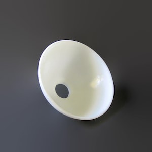 May include: A smooth, off-white, bowl-shaped lamp shade component with a circular opening at the base. The object features a clean, curved silhouette and a matte finish, designed to diffuse light evenly through its semi-translucent material.