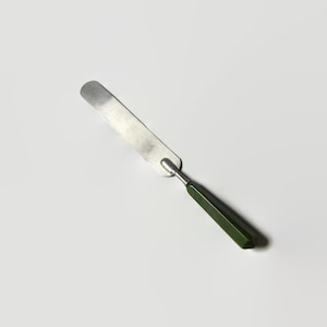 May include: A silver metal spatula with a dark green handle. The spatula is used for spreading and mixing paint.