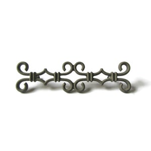 May include: A silver-toned metal decorative accent piece with a scroll design. The piece is made of metal and has a dark gray finish.