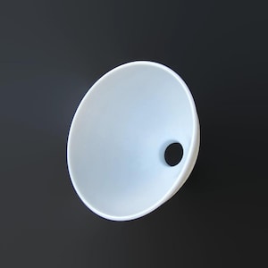 May include: A white, bowl-shaped object with a circular hole on the side. The object has a smooth, curved surface and is set against a dark background. The design is minimalist and modern.