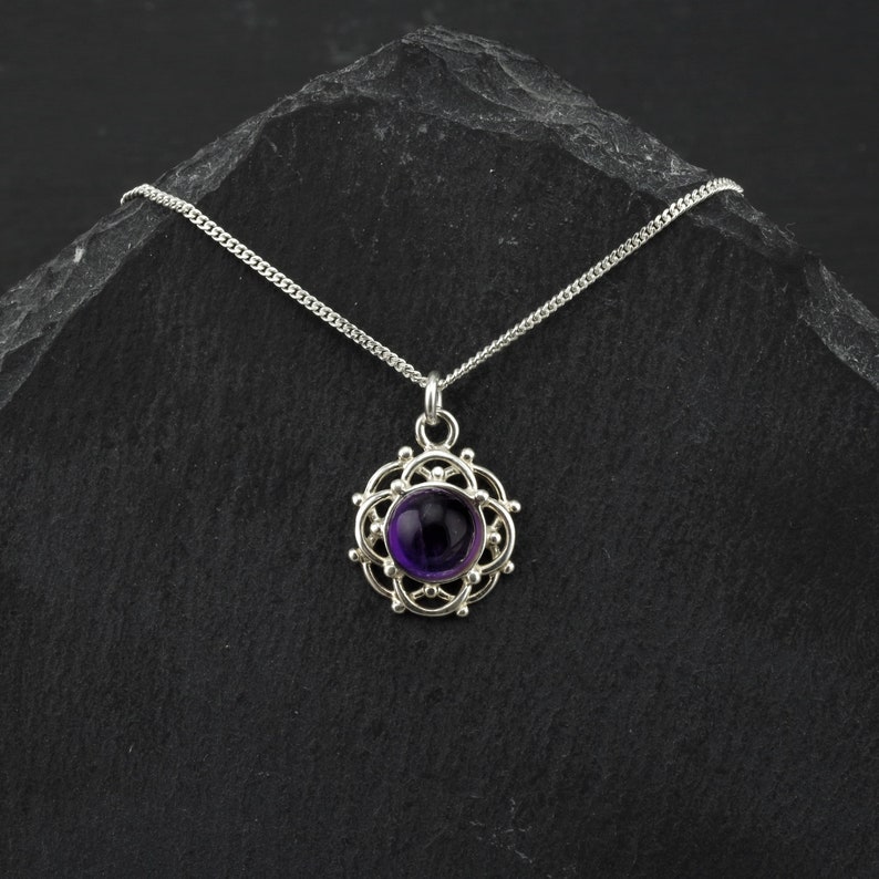 May include: A silver necklace with a purple amethyst gemstone pendant set in a delicate silver filigree design.