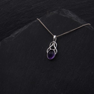 May include: A silver necklace with a purple amethyst stone set in a Celtic knot pendant.
