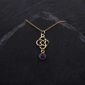 May include: A gold necklace with a Celtic knot pendant and a purple gemstone. The necklace is on a black background.