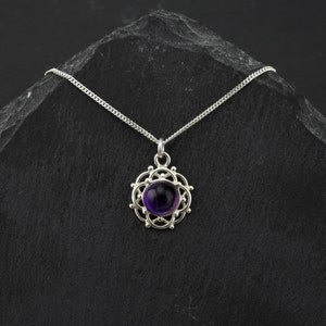 May include: A silver necklace with a purple amethyst gemstone pendant set in a delicate silver filigree design.