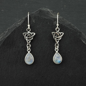 May include: Silver Celtic knot earrings with teardrop moonstone pendants. The earrings have a silver hook fastening.