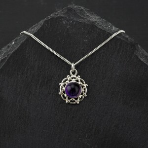 May include: A silver necklace with a purple amethyst gemstone pendant set in a delicate silver filigree design.