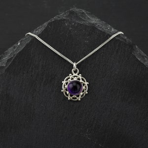 May include: A silver necklace with a purple amethyst gemstone set in a delicate silver filigree pendant.
