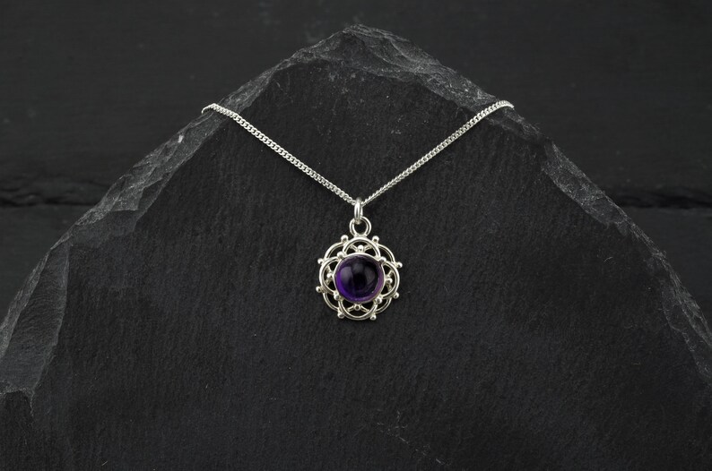 May include: A silver necklace with a purple amethyst gemstone set in a delicate silver filigree pendant.