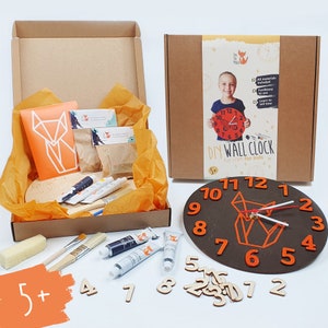 May include: A DIY wall clock craft kit for children aged 5 and over. The kit includes a wooden clock face, paint, brushes, and number stickers. The clock face features a fox design and the words "DIY Wall Clock" and "Fun craft for kids".