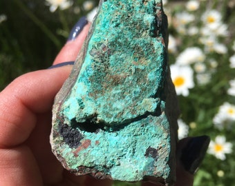 May include: A rough, green and brown, irregularly shaped rock with a smooth, teal-colored surface. The rock is a natural mineral specimen.