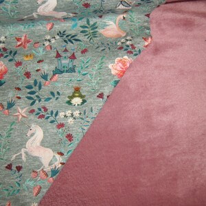 K&ouml;nnte beinhalten: Ein gr&uuml;ner Stoff mit einem wei&szlig;en Einhorn, einem rosa Flamingo und einem Blumenmuster. Der Stoff wird mit einem einfarbigen, staubigen rosafarbenen Stoff kombiniert.