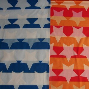May include: Two fabric swatches with a repeating pattern of white stars on a blue and orange striped background. The fabric on the left has a white background with blue stripes and the fabric on the right has an orange background with red stripes.