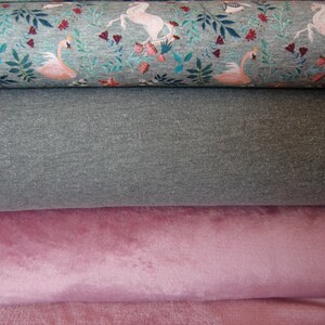 K&ouml;nnte beinhalten: Drei Stoffrollen, eine mit einem rosa Flamingo- und Einhorn-Druck, eine grau und eine rosa.