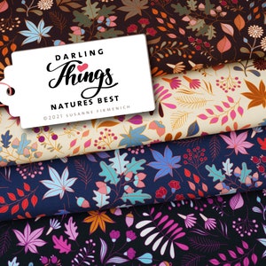 Könnte beinhalten: Stoffmuster mit floralen und Blattmustern in Braun-, Creme-, Marine- und Schwarztönen. Ein weißes Etikett mit dem Text "DARLING Things NATURES BEST" ist angebracht. Die Stoffe zeigen Herbstfarben.