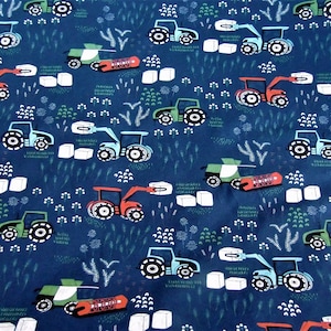 May include: A blue fabric with a repeating pattern of green and red tractors hauling bales of hay. The tractors are stylized and have a whimsical look. The background is a dark blue.