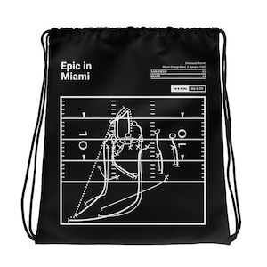 Puede incluir: Mochila negra de cordón con un diagrama de jugada de fútbol americano blanco y el texto "Epic in Miami". El diagrama de jugada muestra la última jugada del Super Bowl XVII, donde los Miami Dolphins derrotaron a los San Diego Chargers 38-41.