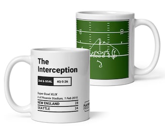 May include: Two white ceramic mugs. One mug features the text "The Interception" with game details. The other mug displays a green football field diagram. The mugs are designed for sports fans.