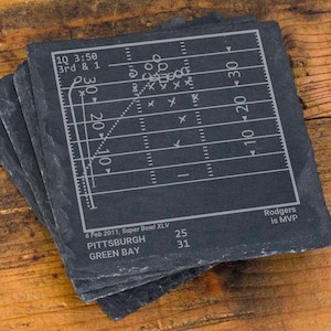 May include: Black slate coasters with a white football field design. The score is 31 to 25. The text "Rodgers is MVP" is at the bottom. The text "6 Feb 2011, Super Bowl XLV" is at the bottom. The text "PITTSBURGH 25 GREEN BAY 31" is at the bottom.
