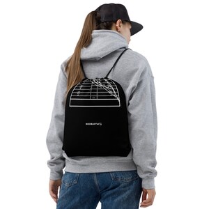 Puede incluir: Mochila con cordón negra con un diagrama de campo de fútbol blanco. La palabra "PLAYBOOK" está impresa en blanco. La mochila tiene cordones negros y se lleva sobre los hombros.