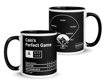 Może przedstawiać: Czarno-biały ceramiczny kubek z napisem "Cain's Perfect Game" i schematem boiska do baseballu. Kubek wyświetla również wynik meczu i szczegóły drużyny. Kubek ma czarny uchwyt i wnętrze.
