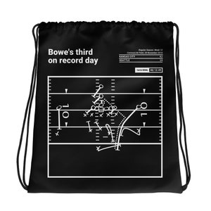 Puede incluir: Una bolsa de cordón negro y blanco con un diagrama de jugada de fútbol y el texto "Bowe's third on record day". El diagrama de jugada muestra un campo de fútbol con jugadores y el balón. El texto "Regular Season: Week 12" está en la parte superior de la bolsa. El texto "CenturyLink Field, 28 November 2010" está debajo del texto "Regular Season: Week 12". El texto "KANSAS CITY 42" está en el lado izquierdo de la bolsa. El texto "SEATTLE 24" está en el lado derecho de la bolsa. El texto "1st & GOAL 4Q 12:49" está en la parte inferior de la bolsa.