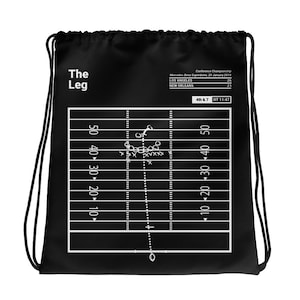 Puede incluir: Bolsa de cordón negro y blanco con un diseño de campo de fútbol americano. El campo muestra la jugada del Campeonato de la NFC de 2019 entre los Los Angeles Rams y los New Orleans Saints. El texto "The Leg" está en la parte superior de la bolsa.