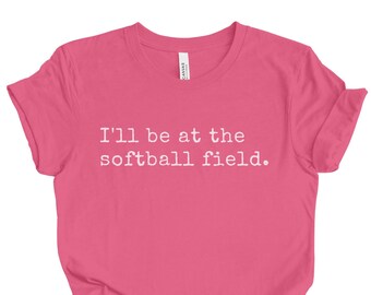 May include: Pink t-shirt with the text "I'll be at the softball field."