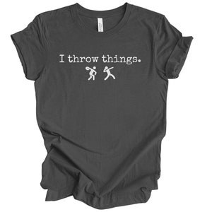 May include: A dark gray t-shirt with the text "I throw things." in white. Two stick figures are shown throwing a ball to each other.