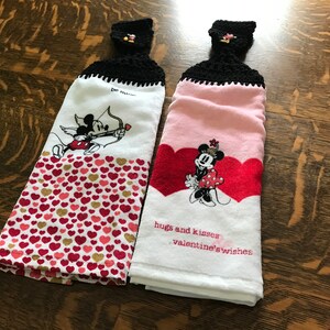 May include: Two white kitchen towels with red hearts and Mickey Mouse and Minnie Mouse Valentine's Day designs. The towels have black crocheted hanging loops and the text "hugs and kisses valentine's wishes" is on one towel.