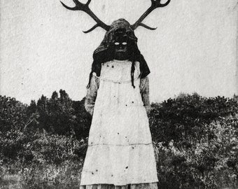 May include: Black and white photograph of a person wearing a white dress and a mask with antlers. The person is standing in a field.