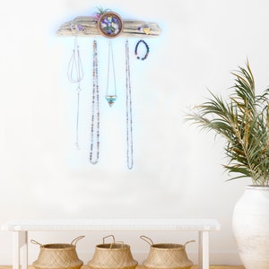 May include: A driftwood jewellery organiser with a small bowl filled with colourful stones. The organiser has hooks for hanging necklaces and earrings. Three woven baskets are in the foreground.