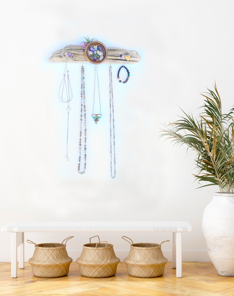 May include: A driftwood jewellery organiser with a small bowl filled with colourful stones. The organiser has hooks for hanging necklaces and earrings. Three woven baskets are in the foreground.