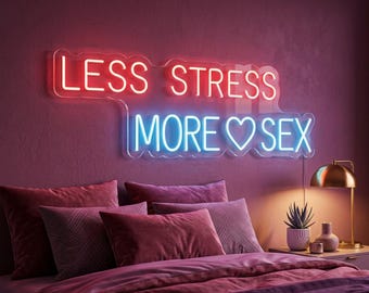 Pode incluir: Um letreiro de néon montado na parede com o texto LESS STRESS em vermelho e MORE SEX em azul, com um símbolo de coração entre as palavras. O letreiro está fixado numa parede escura acima de uma cama com almofadas e um candeeiro.