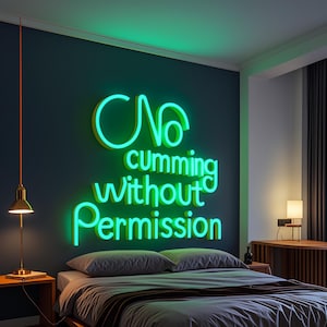May include: A bedroom scene featuring a neon green sign on a dark blue wall. The sign reads "No cumming Without Permission" in a playful font. A bed with gray bedding is in the foreground, with a bedside table and lamp on either side.