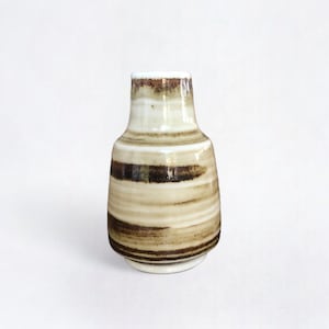 May include: A small, white ceramic vase with brown and beige stripes. The vase has a rounded body and a narrow neck.