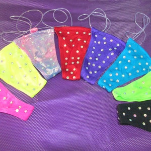 以下が含まれることがあります： 透明なゴム製のストラップが付いた、8色のキラキラしたスパンコールのついたTバックの詰め合わせ。各Tバックは異なる色で、小さなキラキラ光るラインストーンで飾られています。