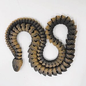 May include: A brown and black plastic snake toy. The snake is curled up in a figure of eight shape.