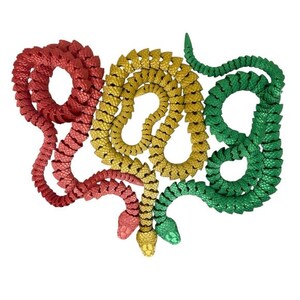 May include: Three plastic toy snakes, one red, one yellow, and one green, are coiled together in a decorative pattern.