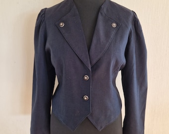 Puede incluir: Una chaqueta azul oscuro con cuello de pico, mangas largas y silueta ajustada. La chaqueta tiene cuatro botones en la parte delantera y dos botones decorativos en los hombros.