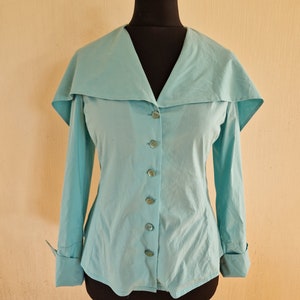 May include: A light blue long-sleeved blouse with a large, wide collar and button closure.