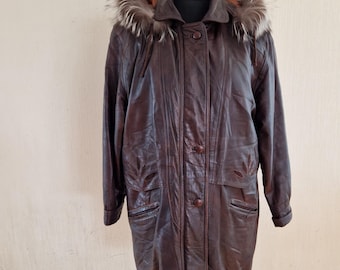 May include: A dark brown leather coat with a fur-trimmed hood. The coat has a button-up front, pockets, and decorative stitching. The coat is displayed on a mannequin. The coat is a vintage style.