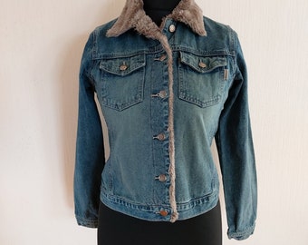 May include: A blue denim jacket with a brown faux fur collar. The jacket has a button closure and two front pockets.