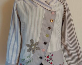May include: A white and grey striped jacket with a collar and a button fastening. The jacket features a flower design and the text "Joyful Days Bravo!" embroidered on the front.