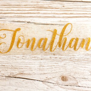 May include: Gold glitter name decal with the name "Jonathan" written in a cursive font.