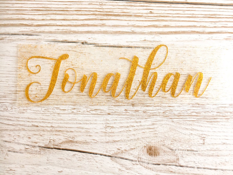 May include: Gold glitter name decal with the name "Jonathan" written in a cursive font.