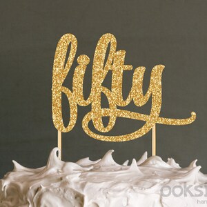 Pode incluir: Topper de bolo de glitter dourado com a palavra "fifty" em fonte cursiva.