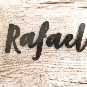 May include: A black glitter vinyl decal with the name "Rafael" written in a cursive font.