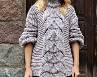 May include: A gray knitted sweater with a cable knit pattern and a turtleneck. The sweater has a loose fit and long sleeves.
